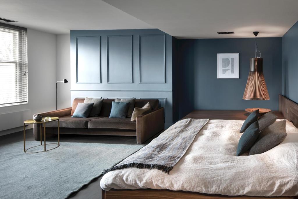 ein Wohnzimmer mit einem Bett und einem Sofa in der Unterkunft COMMUNE suites in Amsterdam