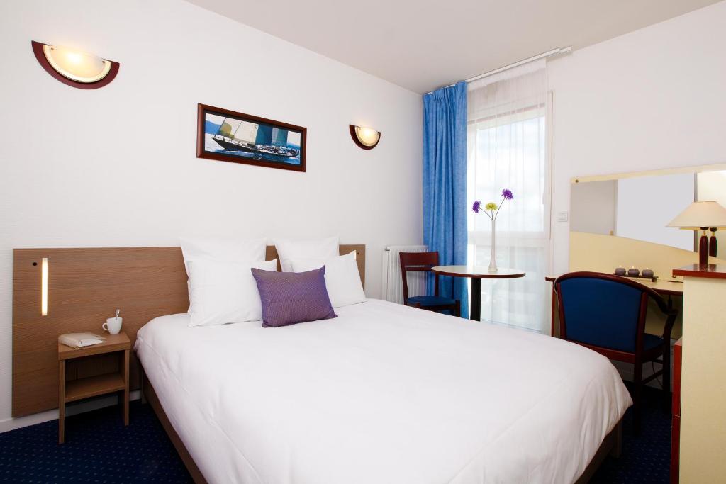 レンヌにあるAppart'City Classic Rennes Beauregardの白い大型ベッドとテーブルが備わるホテルルームです。