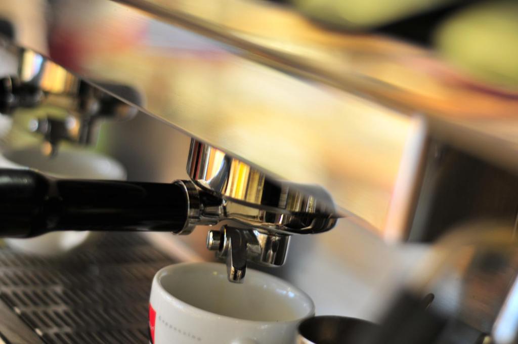 Una cafetera vertiendo café en una taza en AKZENT Hotel Stadt Schlüchtern ***S en Schlüchtern