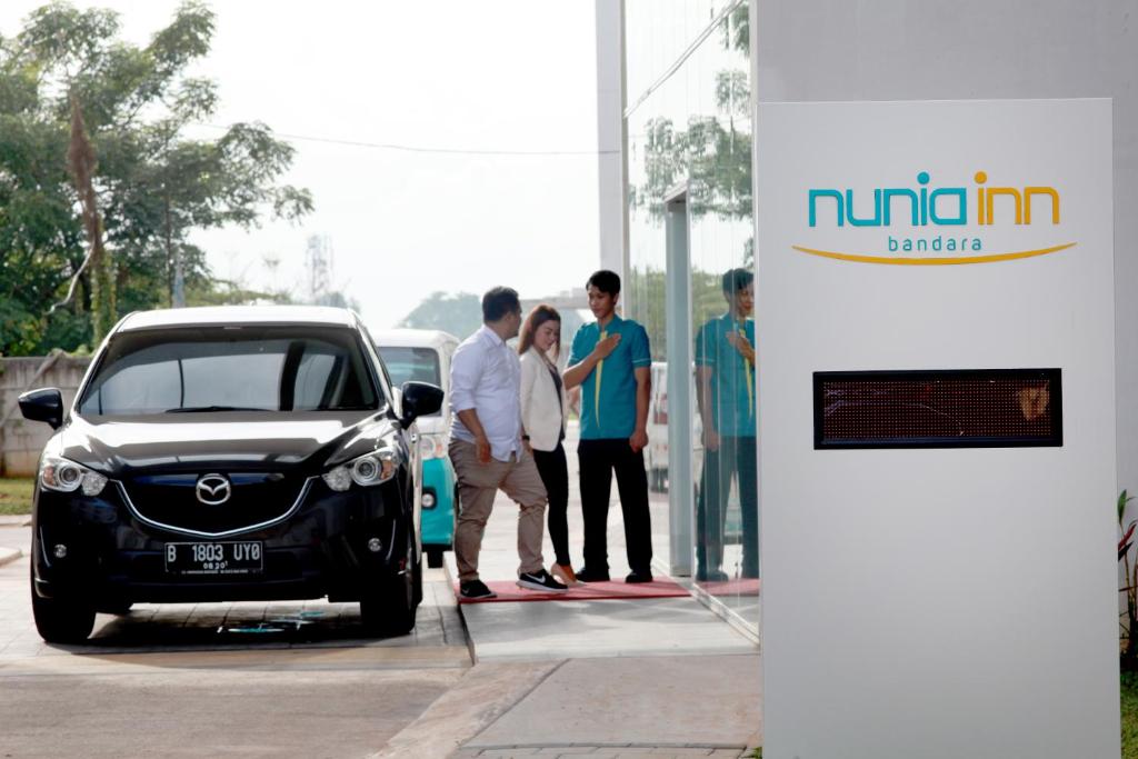 a group of people standing next to a car at a gas station at Nunia Inn Bandara Jakarta in Tangerang