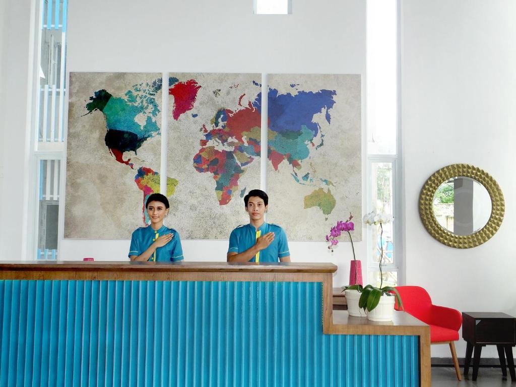 two men standing behind a counter with a map at Nunia Inn Bandara Jakarta in Tangerang