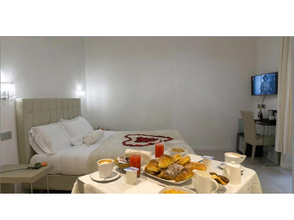 羅馬的住宿－梵蒂岡豪華套房住宿加早餐旅館，一间房间,配有一张床和一张桌子,上面有盘子的食物