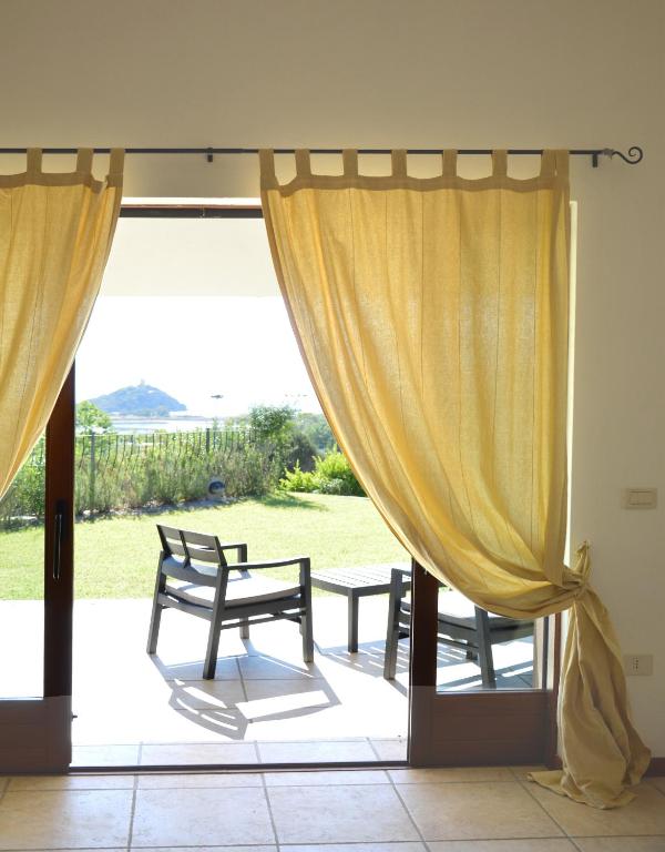 a patio with curtains and a table and a bench at Sa Tirìa in Chia
