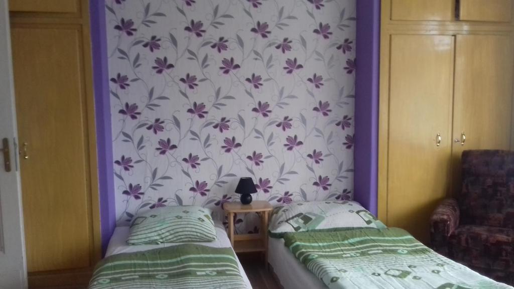 two beds in a room with a wallpaper with flowers at Penzion Uran in Stráž pod Ralskem