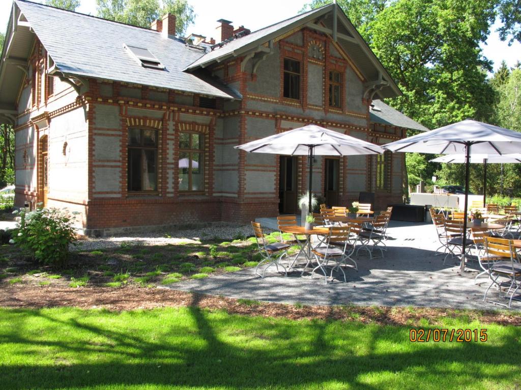 una casa con mesas y sombrillas delante en Forsthaus Sommerswalde, en Sommerswalde