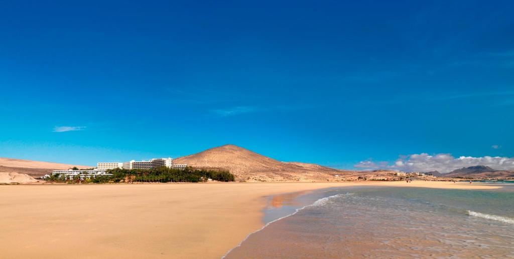 a view of a beach with a building in the background at INNSiDE by Meliá Fuerteventura – Adults Only in Costa Calma