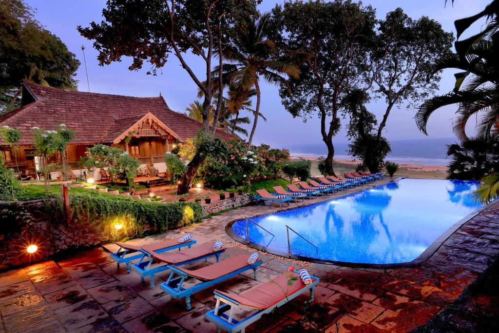 a swimming pool with lounge chairs and a resort at Somatheeram Ayurveda village in Kovalam
