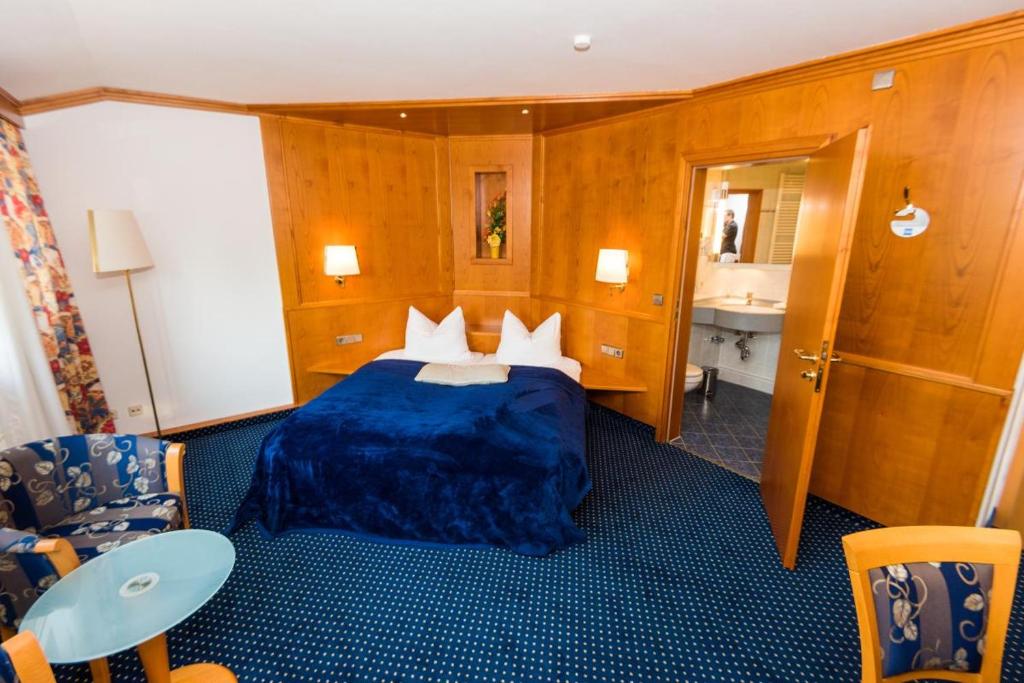シュトゥットガルトにあるホテル アム フォイアゼーのベッド、テーブル、椅子が備わるホテルルームです。