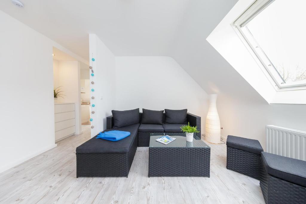 a living room with a black couch and a table at Dünenhaus Steinmarne in Cuxhaven