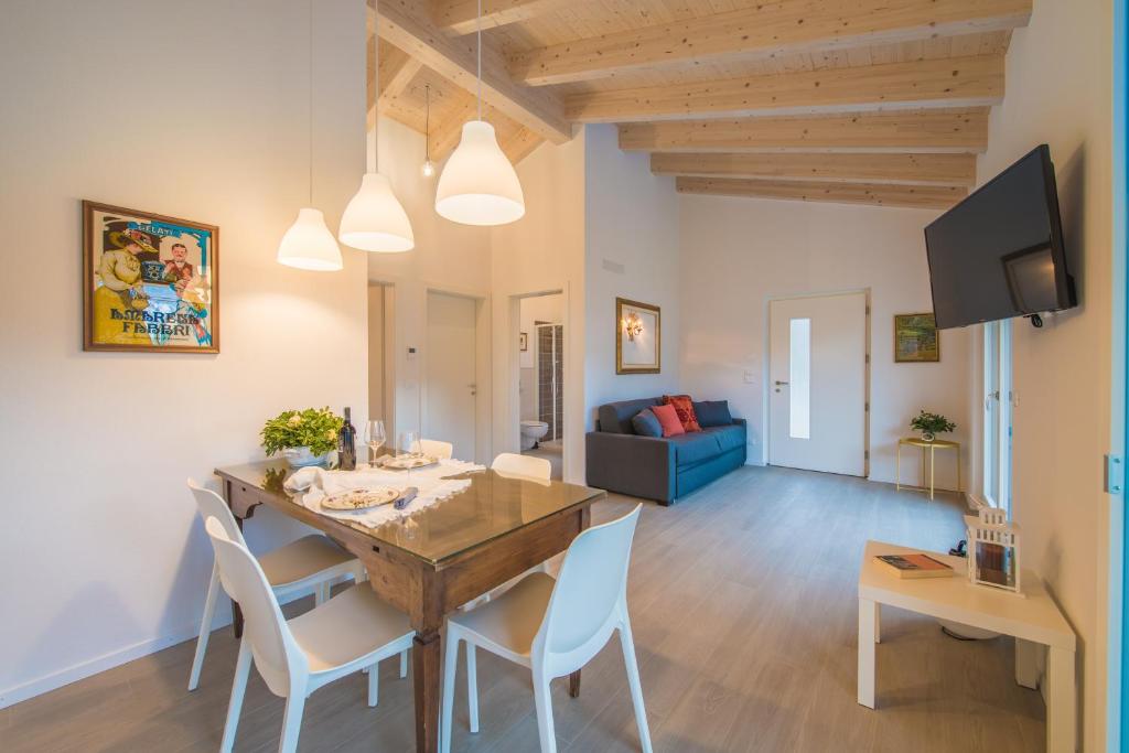 ein Esszimmer und ein Wohnzimmer mit einem Holztisch und Stühlen in der Unterkunft La Gazza Ladra Apartments - Garda Chill Out in Drena