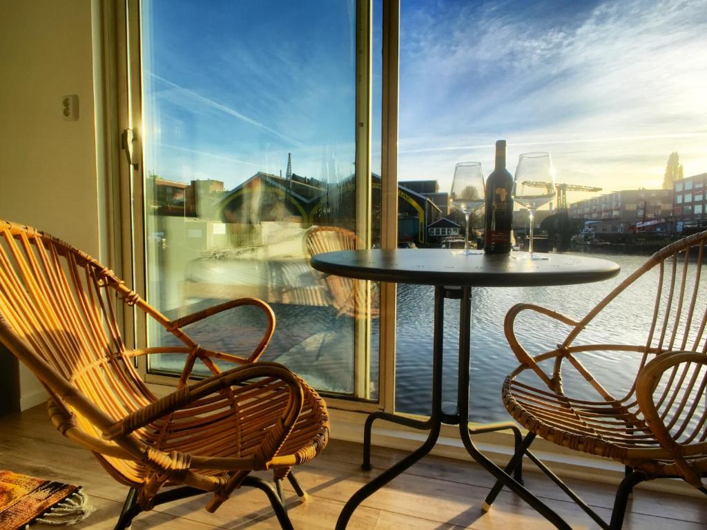 una mesa y sillas en un balcón con ventana en Houseboat Concordia B&B en Ámsterdam