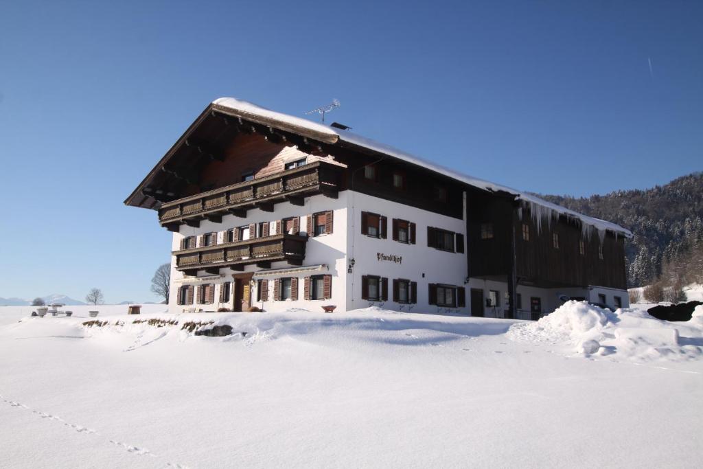 un grand bâtiment dans la neige recouvert de neige dans l'établissement Pfandlhof, à Walchsee