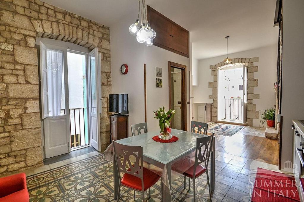 トゥーリにあるAntiche Mura Apartments "Nel Cuore della Puglia"bivani, cucina, terrazzoのダイニングルーム(ガラスのテーブル、椅子付)