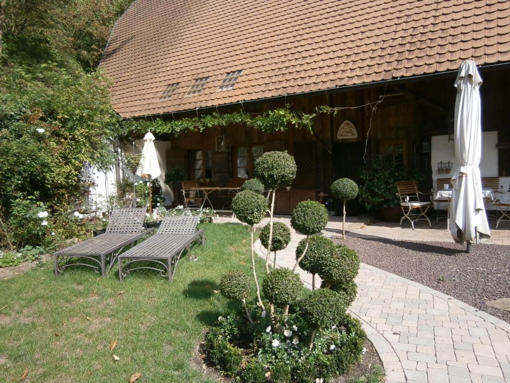 a garden with two benches and an umbrella at Vier Jahreszeiten Idyll in Schuttertal