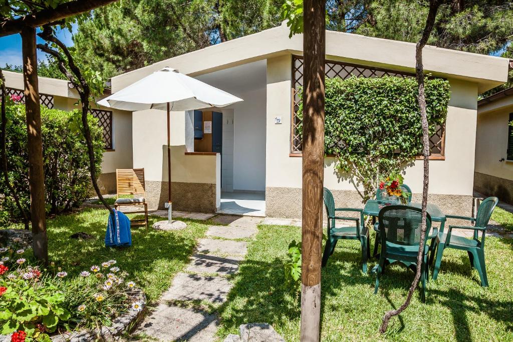 een patio met een tafel en stoelen en een parasol bij Villaggio Residence Torre Saracena in Marina di Camerota