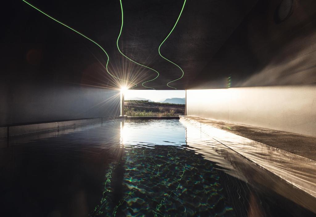 a pool of water with a light at night at Das Wanda in Caldaro