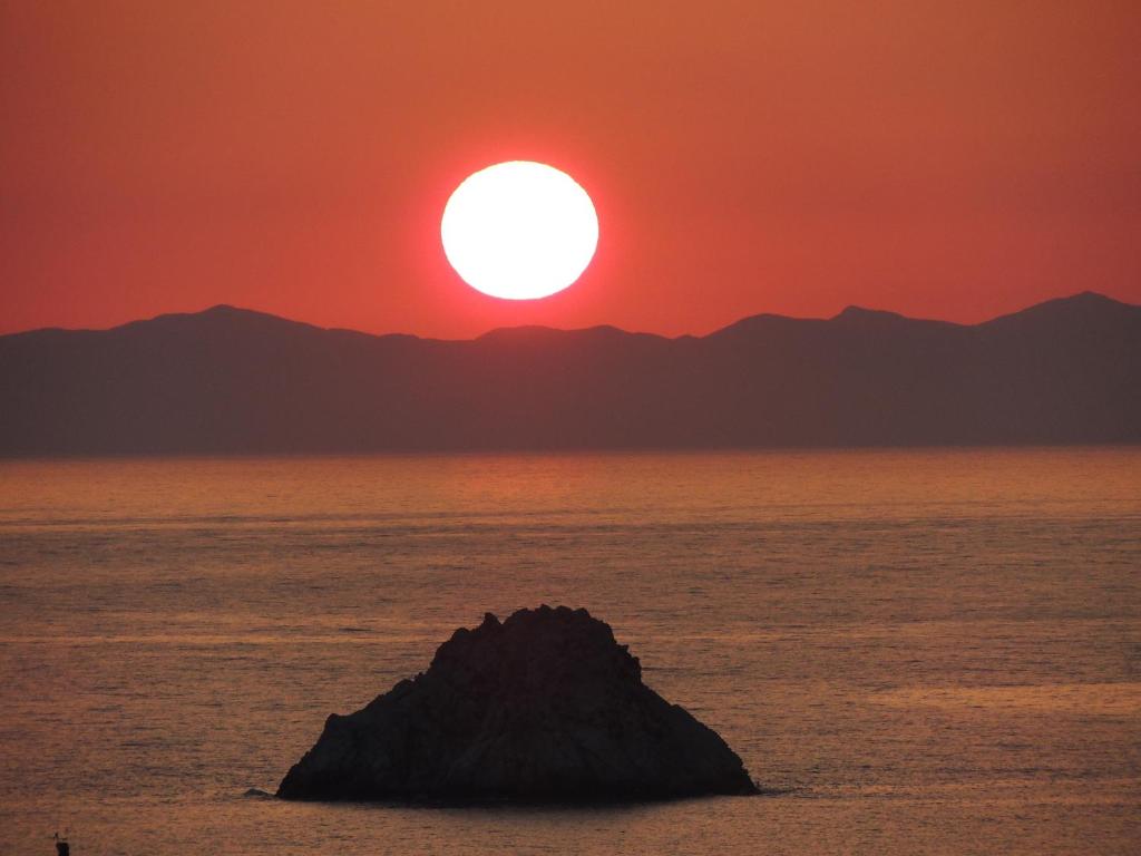 a sunset over the ocean with a rock in the water at Hotel Viticcio in Portoferraio