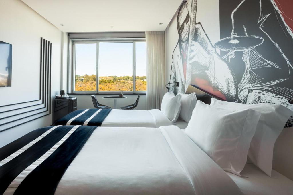 A bright twin room with a large window and music-themed wall mural.