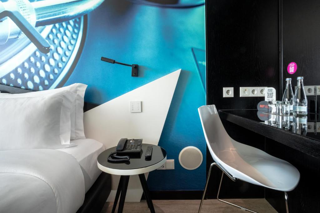 A small in-room work surface beside the bed, with a chair, telephone, outlets and complimentary-looking drinks.
