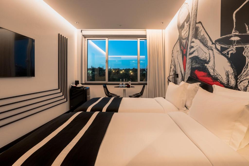 A warmly lit twin room with a music mural and blue evening view.