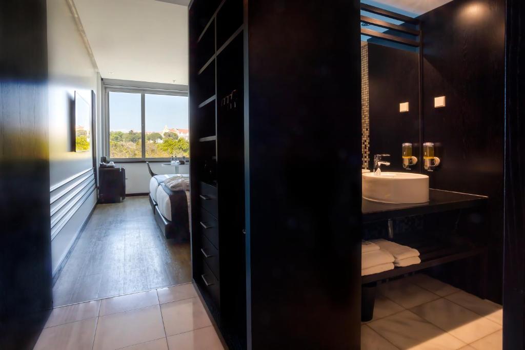 A dark-toned bathroom entrance showing the vanity, toilet, and a view back toward the bedroom window.