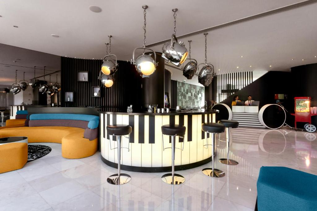 A music-themed lobby bar with a piano counter, stools, and colorful lounge seating.