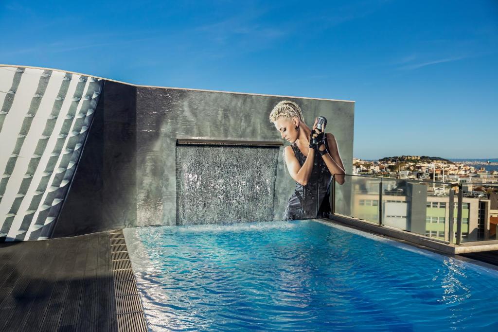 A rooftop pool with a mural wall and city views beyond the glass railing.