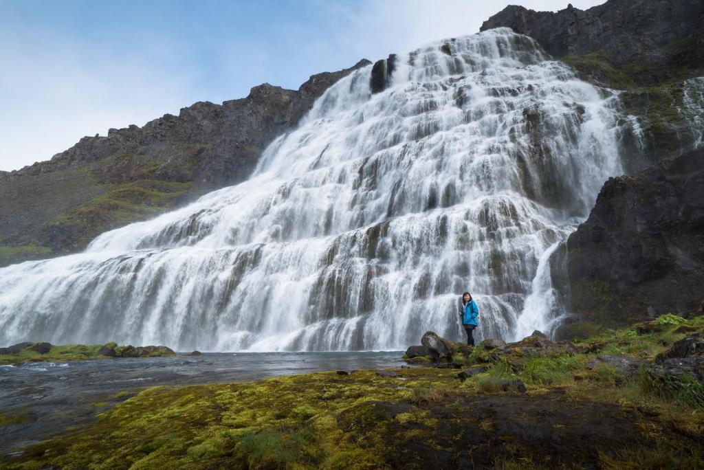 a person standing in front of a waterfall at Fisherman Hotel Westfjords in Suðureyri