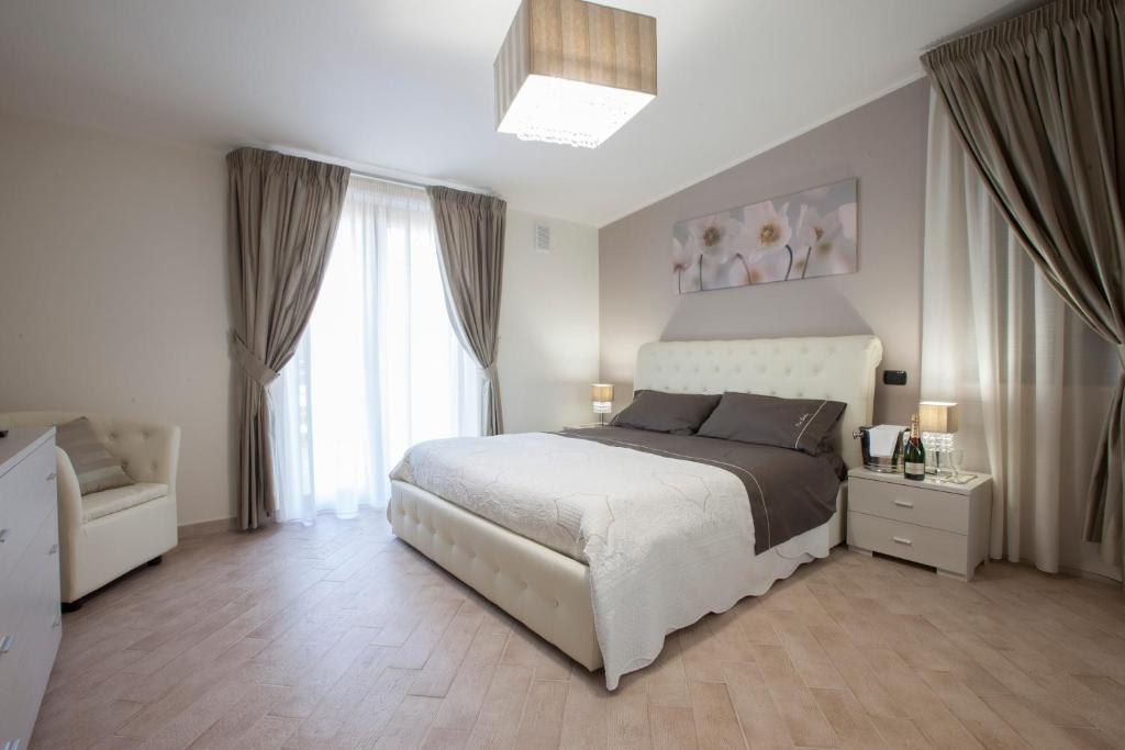 a bedroom with a white bed and a large window at Amira Luxury Apartments in Santa Maria Capua Vetere