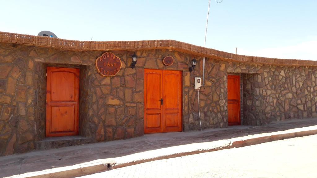 un edificio de piedra con cuatro puertas rojas. en Hostal Casa Flores, en San Pedro de Atacama