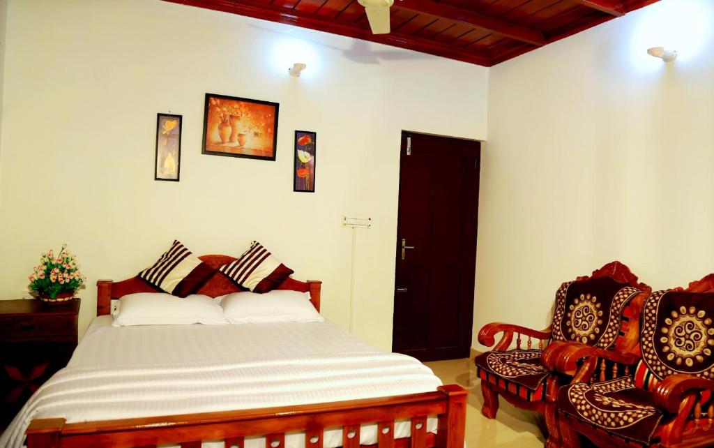 a bedroom with a bed and two chairs at Elroy Homestay in Kalpetta