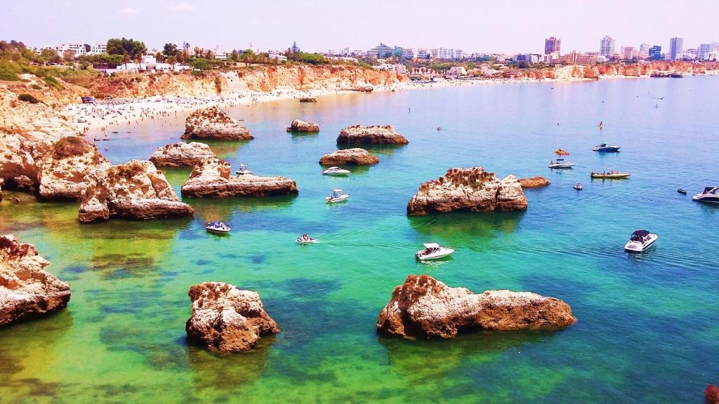 a beach with rocks and people in the water at La Maison dos Prazeres in Portimão