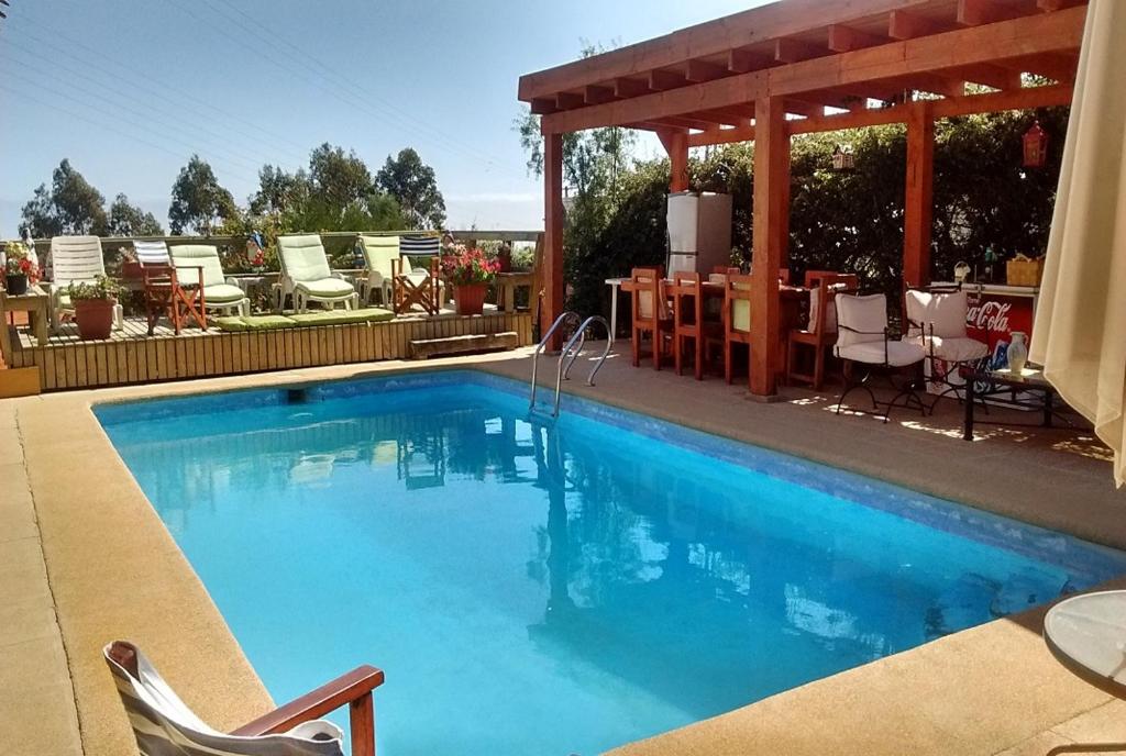 a swimming pool with chairs and a gazebo at Shangrila Tunquen in Tunquen