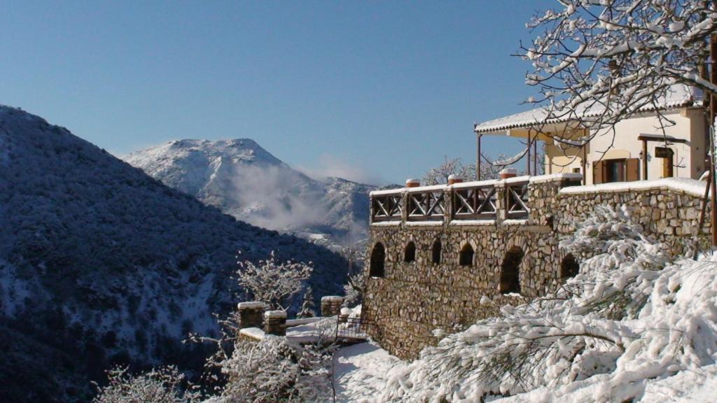 a building in the snow with a mountain in the background at Agnantio studios & suites in Lagadia