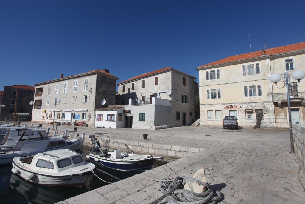 un groupe de bateaux amarrés dans un port de plaisance comportant des bâtiments dans l'établissement Apartment Sali Dugi Otok, à Sali