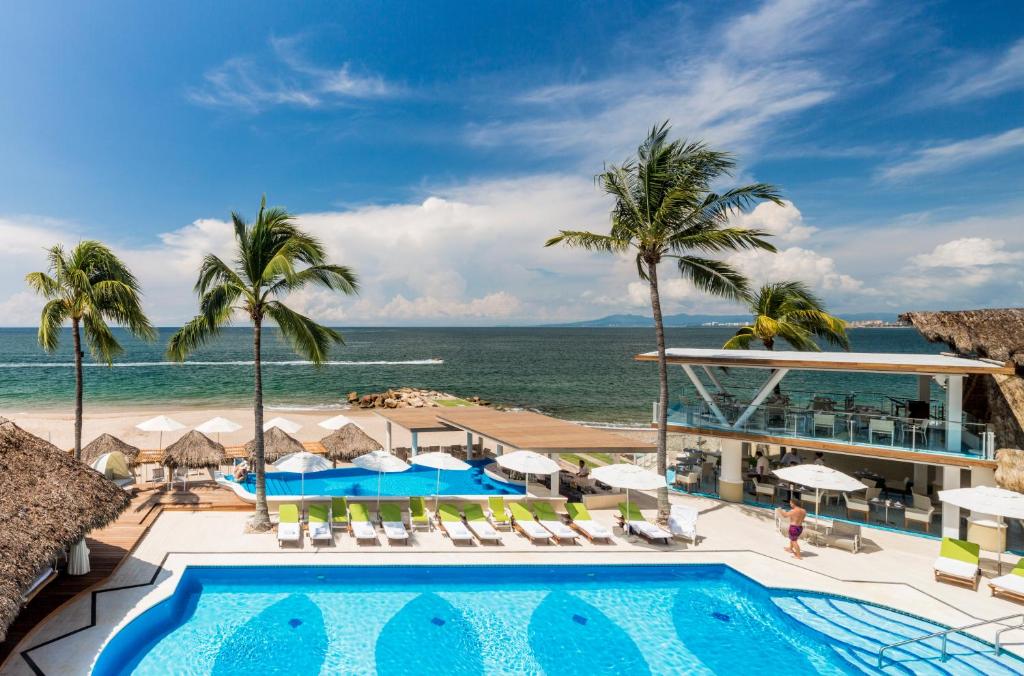 a beach area with a pool, chairs, and a beach umbrella at Villa Premiere Boutique Hotel & Romantic Getaway in Puerto Vallarta