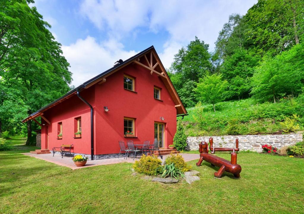 una casa roja con parque infantil en el patio en Apartmánový domek Pod Ucháčem, en Velké Losiny