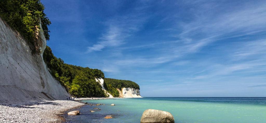 einen Strand mit Felsen und blauem Wasser und einer Klippe in der Unterkunft Ferienpark Bernstein in Dranske
