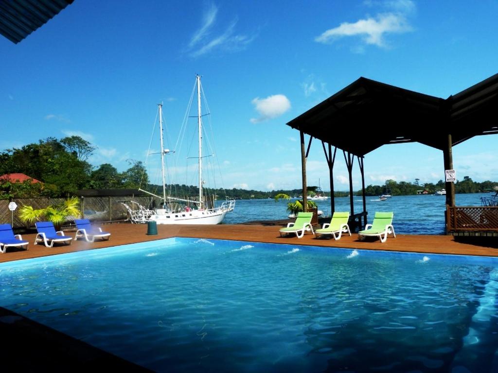 una piscina con sillas y un barco en el agua en Mar Marine Yacht Club en Río Dulce