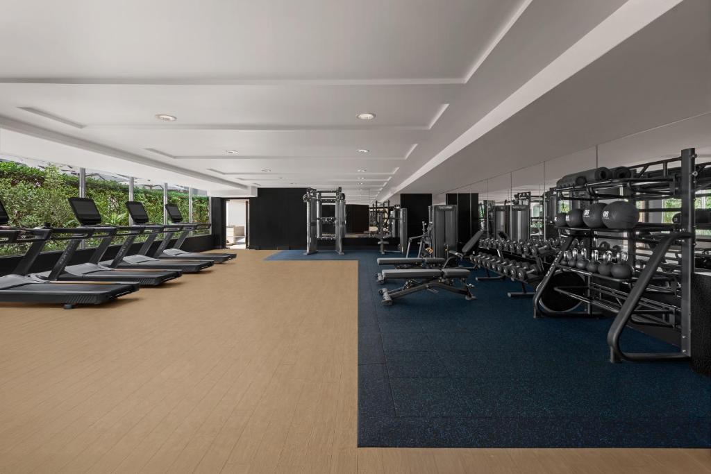 A bright, fully equipped fitness room with treadmills, weights, and strength machines.