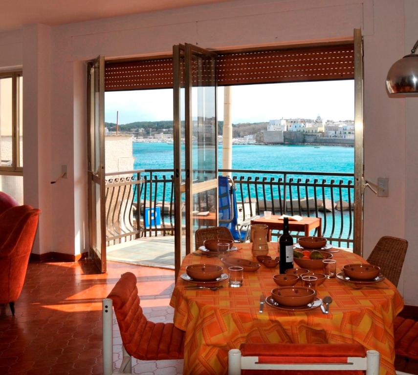 een eetkamer met een tafel en uitzicht op het water bij Otranto in riva al mare in Otranto