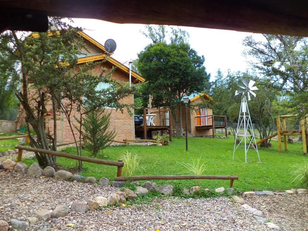una casa con un molino de viento y una casa con un patio en Cabañas Kumelkan en Los Reartes