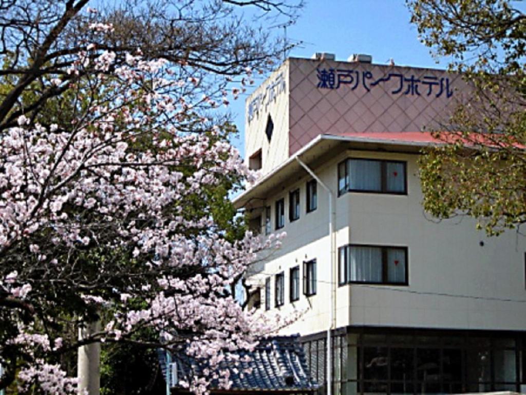 a white building withakuraakura trees in front of it at Seto Park Hotel in Seto
