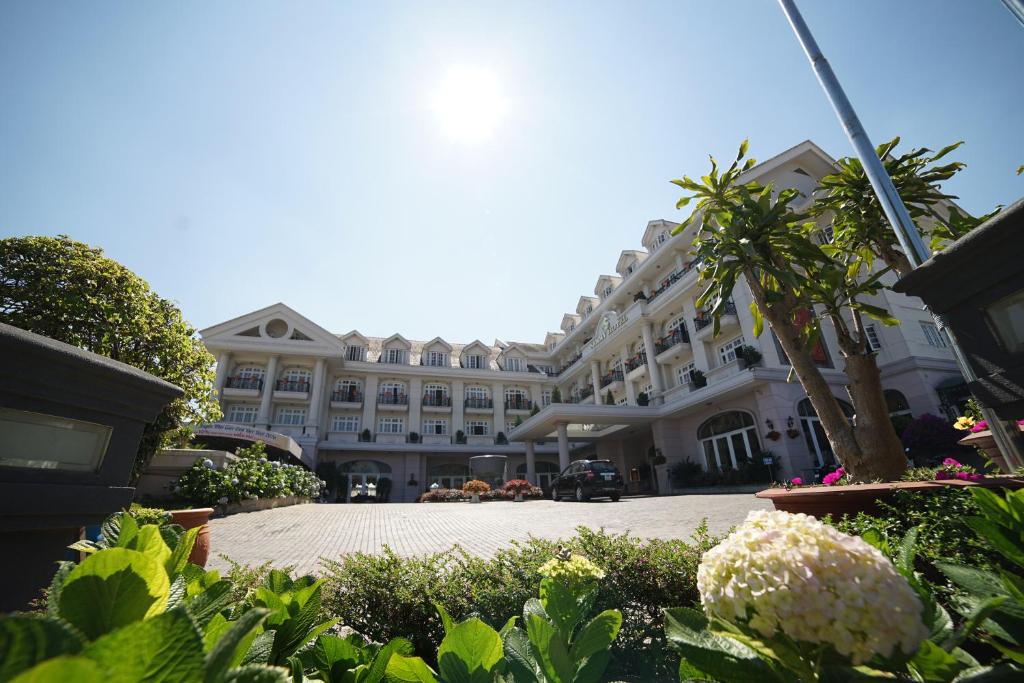 a large building with a palm tree in front of it at Sammy Dalat Hotel in Da Lat