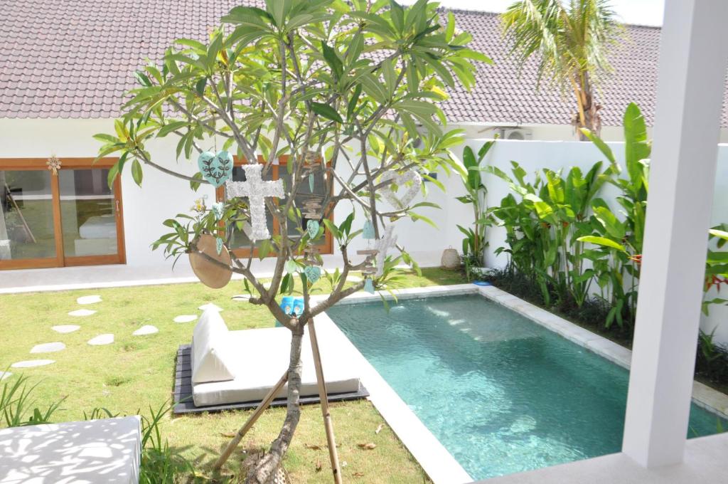 een kruis naast een boom naast een zwembad bij Villa Enjoy in Canggu