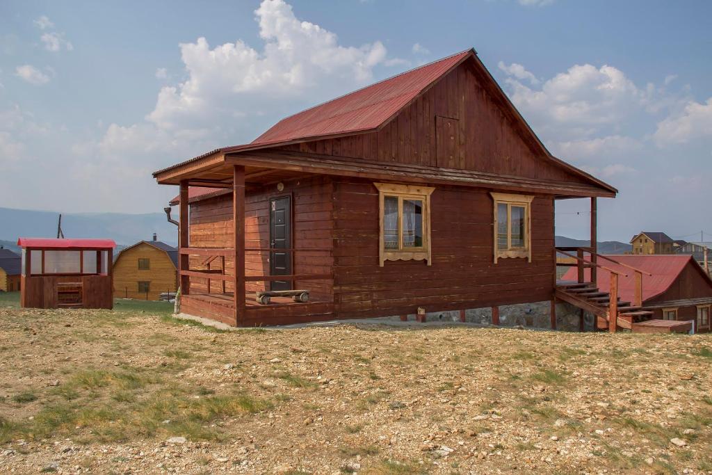 una casa de madera con techo rojo en un campo en Azatey Guest House, en Sakhyurta