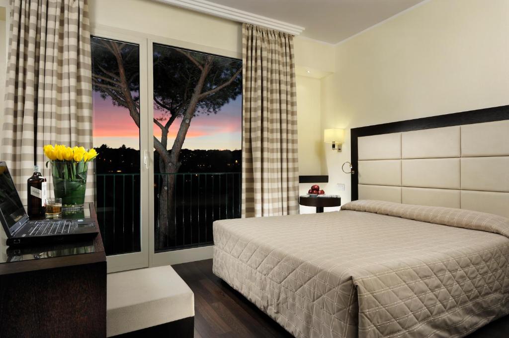 a bedroom with a bed and a window with a tree at Hotel Villa Maria Regina in Rome