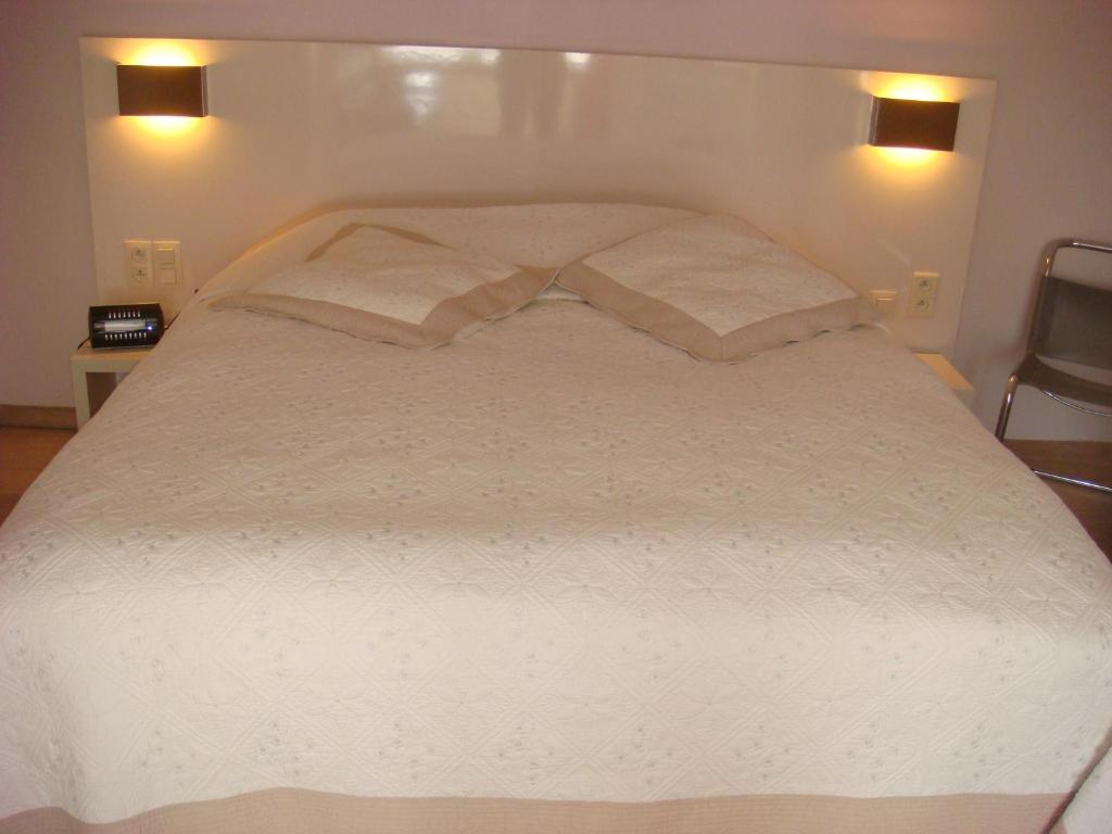 a large white bed with two pillows on it at Gastenkamers Centersuites in Oostduinkerke