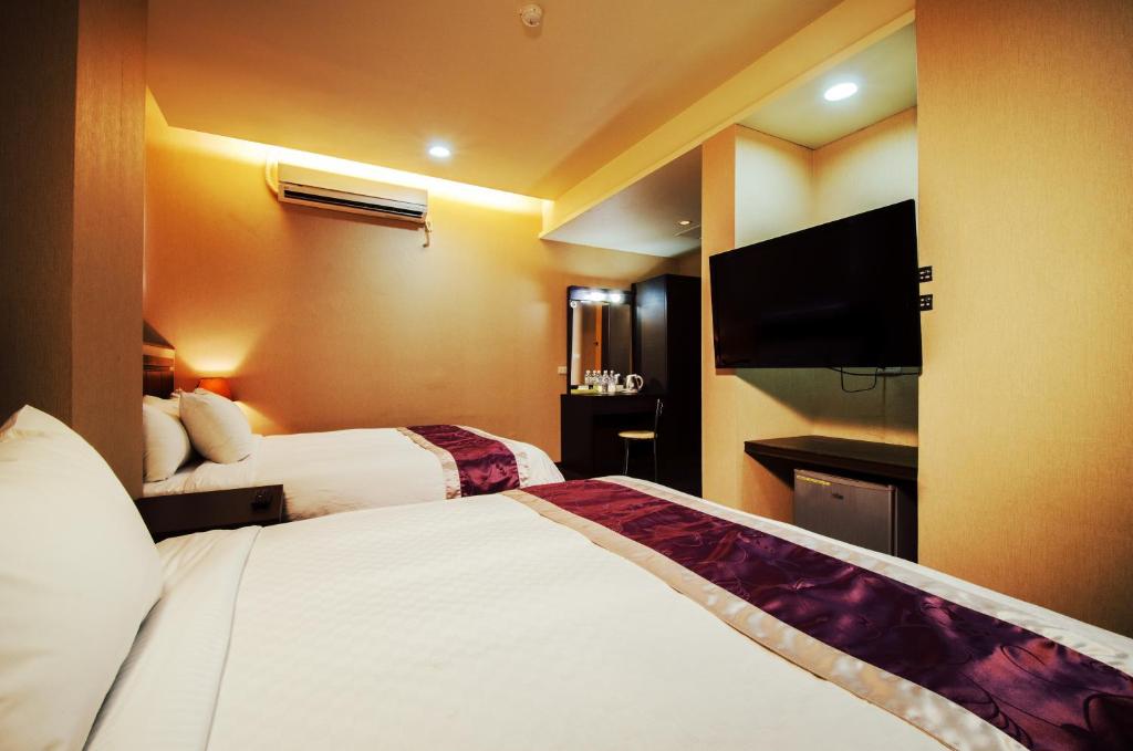 een hotelkamer met 2 bedden en een flatscreen-tv bij King Town Hotel in Luodong