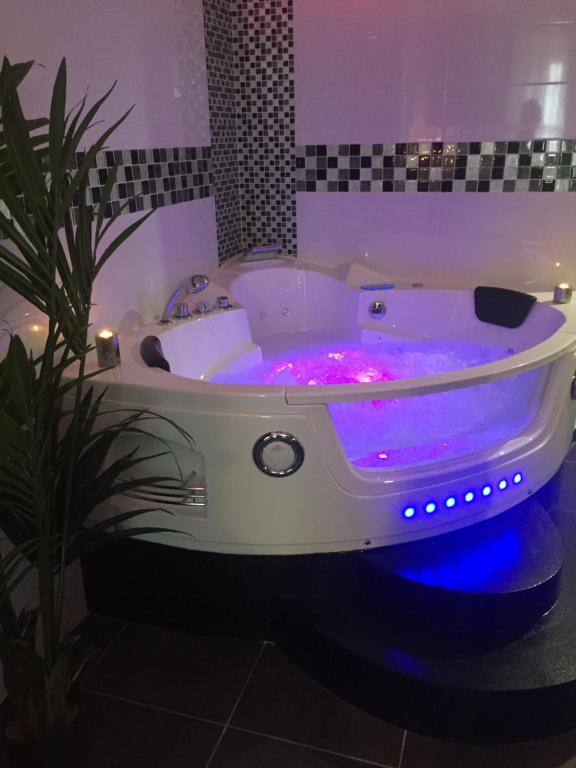 La salle de bains est pourvue d'une baignoire blanche avec des lumières violettes. dans l'établissement Le Love Spa, à Lyon